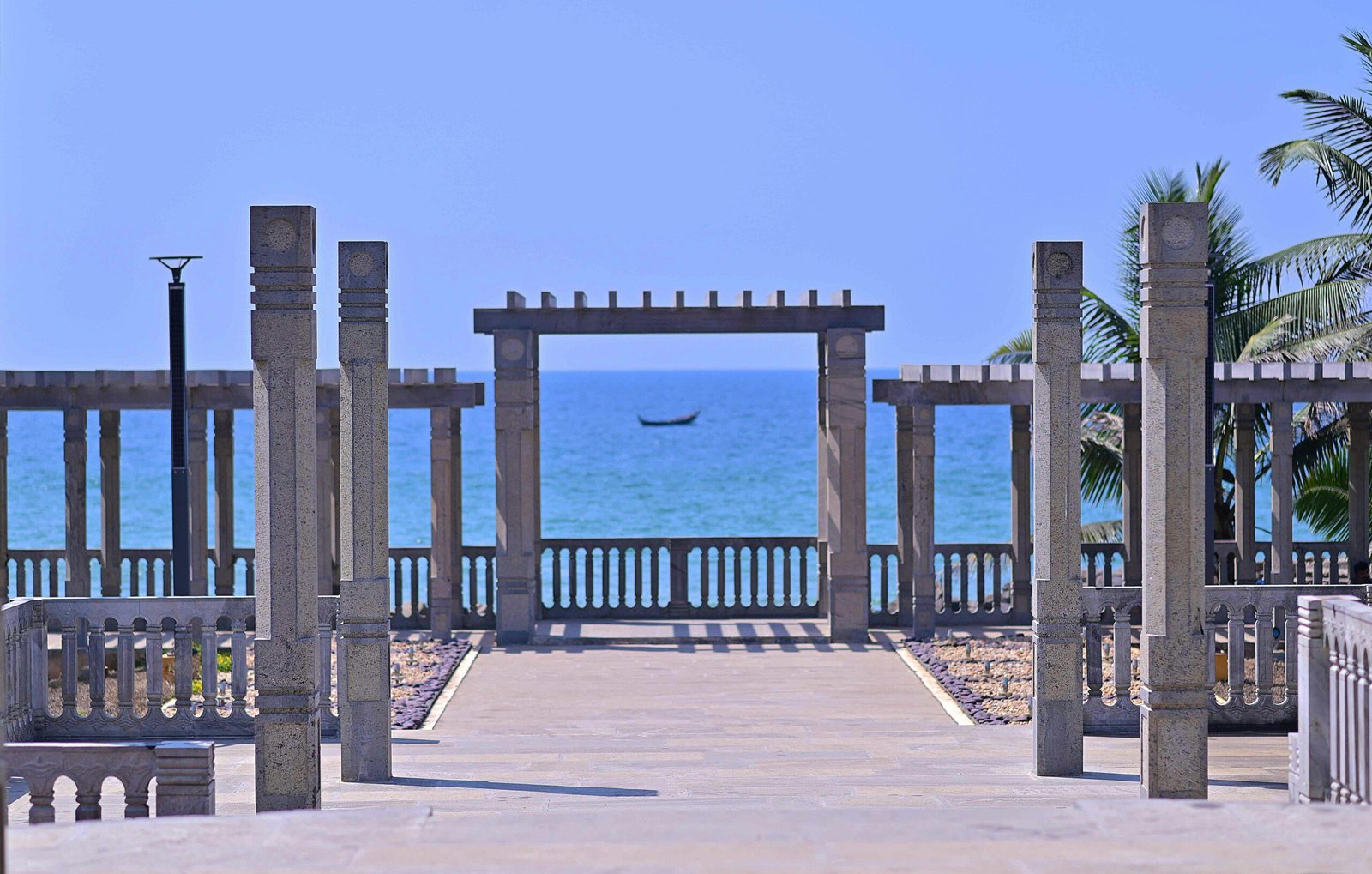 Explore Kovalam Beach's stunning ocean view framed by stone pillars and lush palm trees.