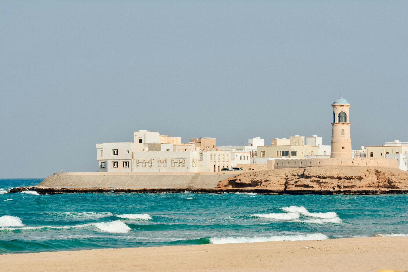 A serene view of Sur Lighthouse and traditional buildings on the Omani coast.